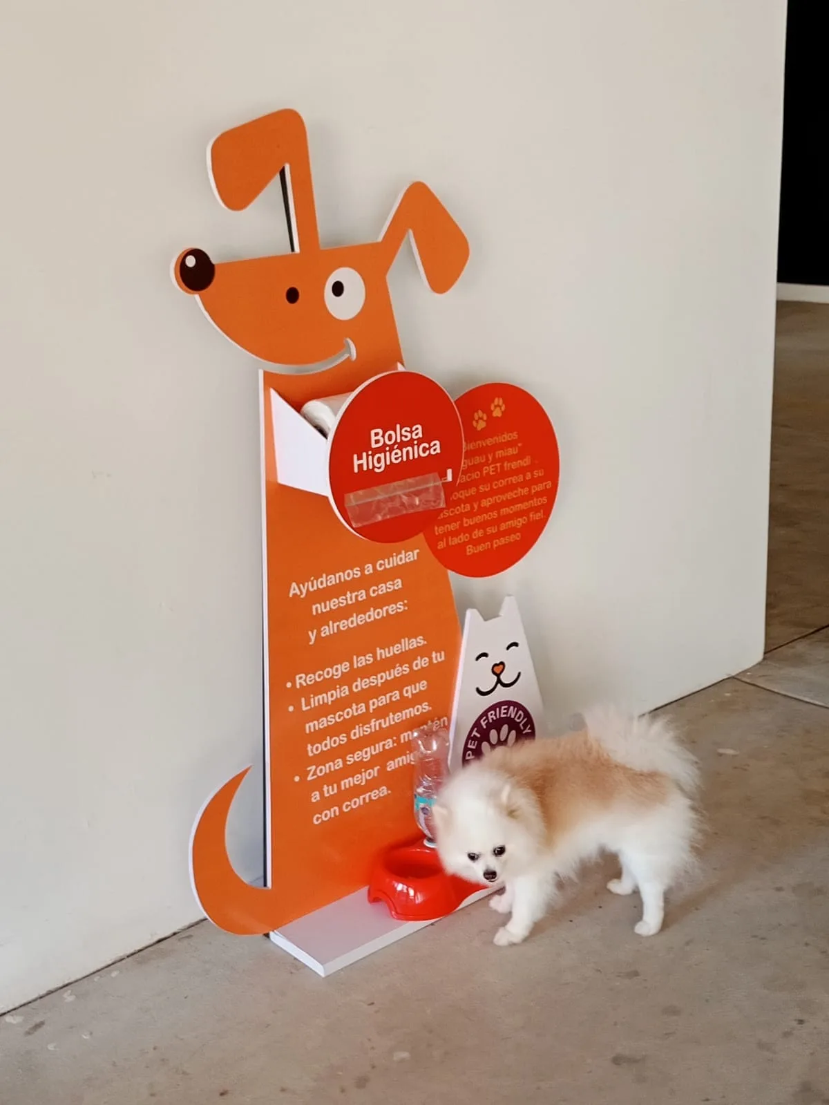 Estación pet-friendly con dispensador de bolsas higiénicas y mascota